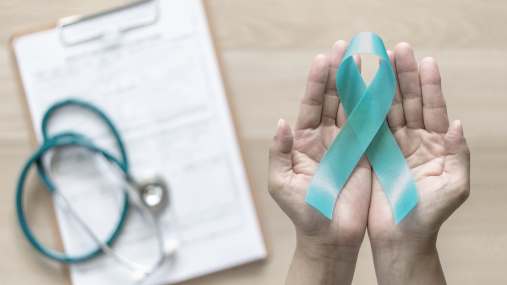 An outstretched hand holding a breast cancer awareness ribbon