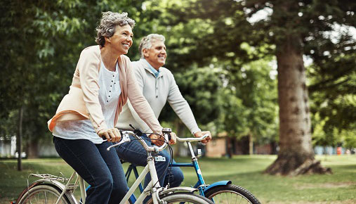 Two older people riding bikes in a park