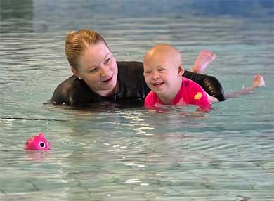 A physiotherapist in the water working with a child