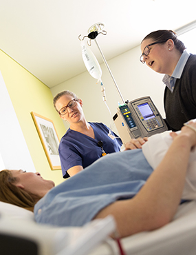 Two nurses talking to a patient.