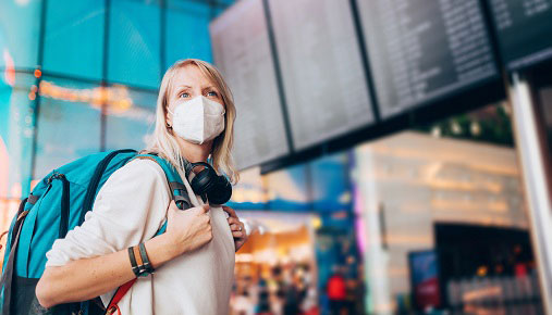 A woman walking in an airport wearing a face mask