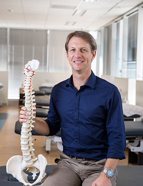 Professor Mark Hancock, with an anatomical model of a spinal column.